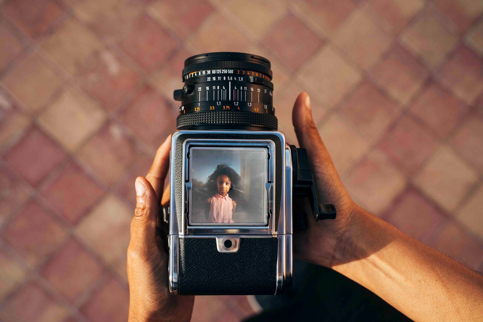 Looking down on an old camera, taking a photo of a young afro girl